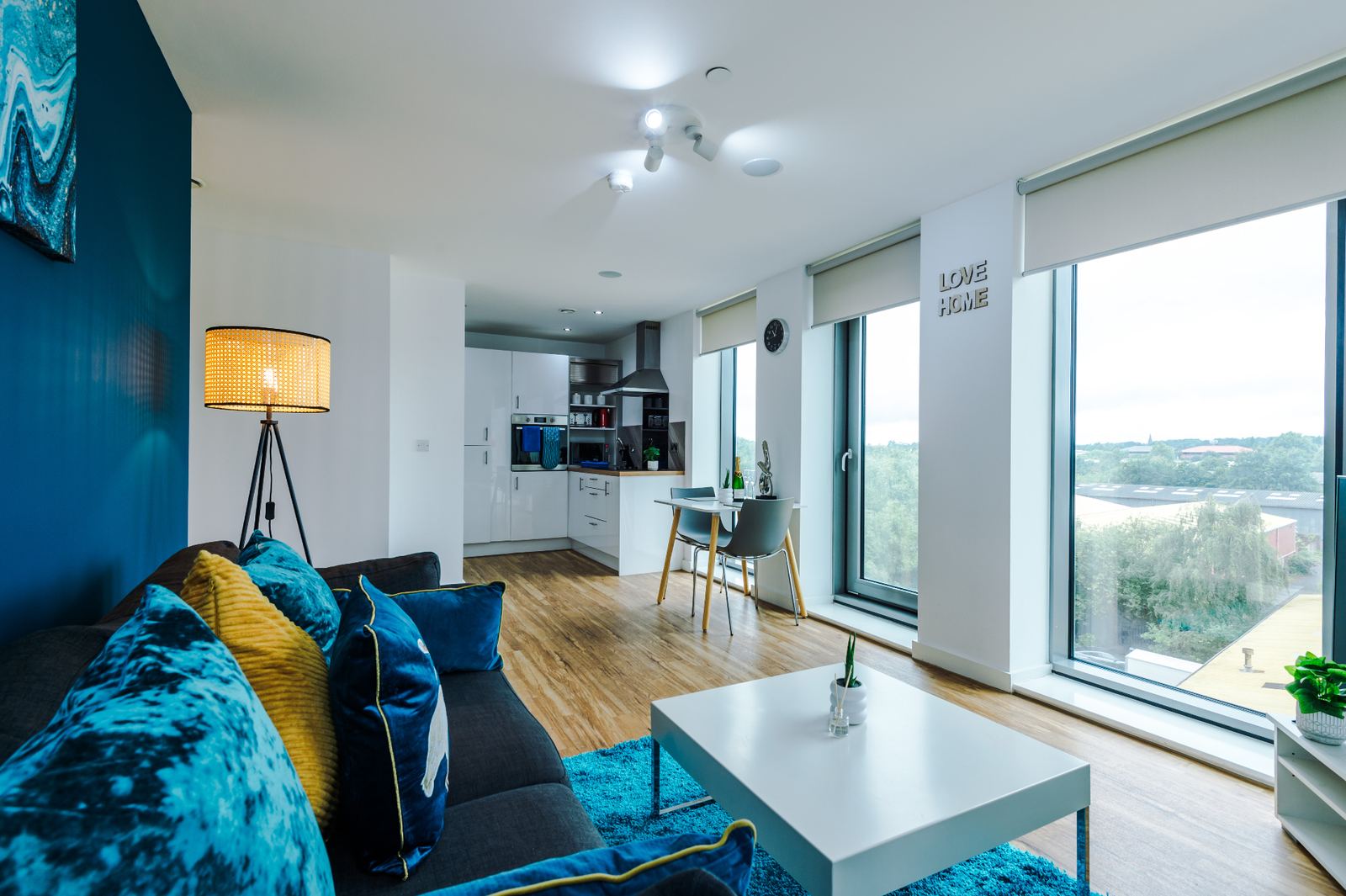 Open-plan staged apartment with lounge seating, kitchen and full-height windows