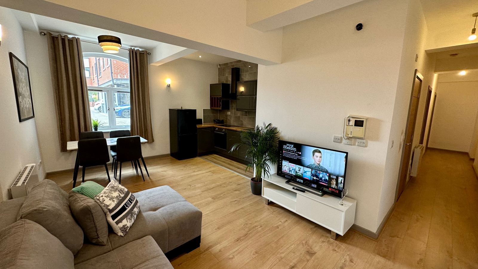 Open-plan staged living and kitchen with grey sofa, dining set and styled accessories