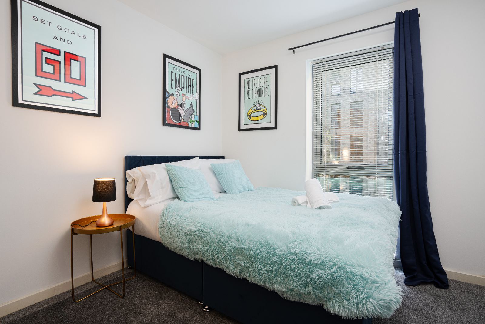 Styled bedroom with motivational artwork, navy curtains and accent lighting